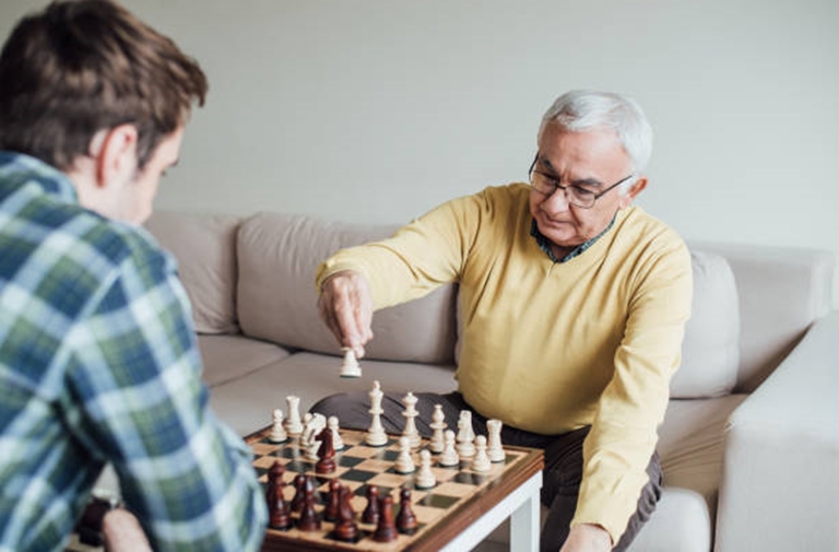 Proveer at Port City | Senior man playing chess outside with visitors