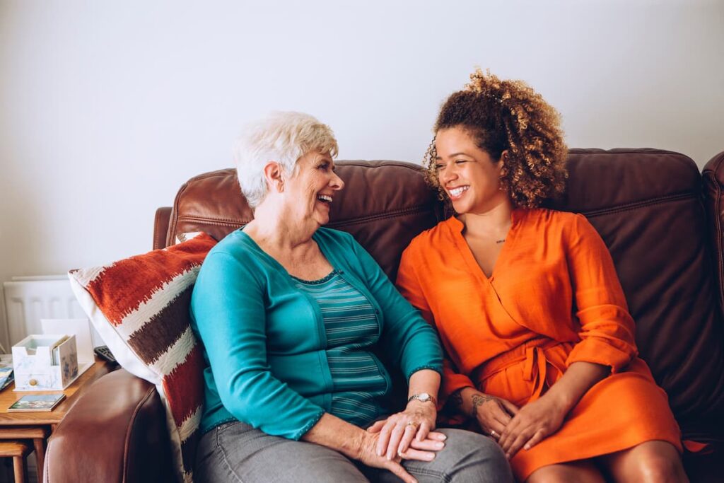 Proveer at Port City | Happy senior woman sitting on couch talking with caregiver